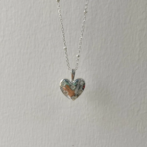 Macro shot of silver heart pendant with cubic zirconia on a minimalist bead chain