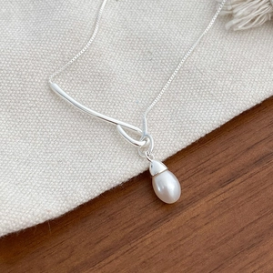 Close-up of S925 silver stamp on pearl necklace with elegant drop-shaped pendant