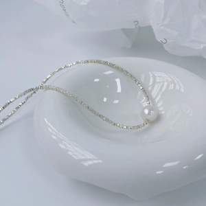 Dettaglio della catena in argento sterling S925 e perla bianca lucida su vassoio ceramico