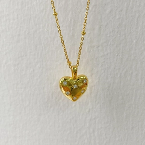 Detailed close-up of a 3D gold heart pendant necklace with six inlaid white zircons