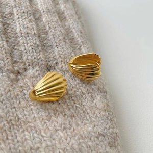 Elegant gold ribbed shell earrings S925 sterling silver on knit fabric background