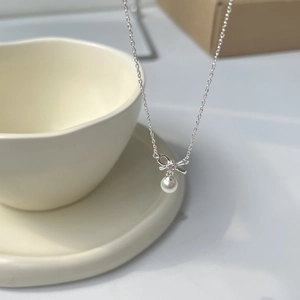 Detail of silver bow pendant with pink gemstone and white pearl on necklace