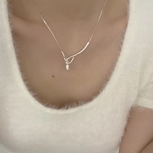 Detail shot of a minimalist silver chain necklace with pearl and organic curved pendant