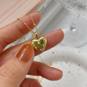 Close-up of a delicate gold heart pendant with small sparkling zircon stones on a fine chain