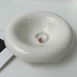 Detail of adjustable 925 silver ring with oval strawberry quartz on ceramic tray
