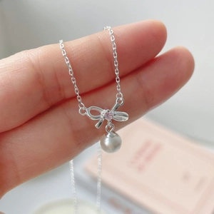 Close-up of S925 silver bow necklace with pink gemstone and white pearl pendant