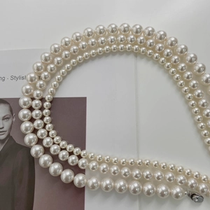 Detailed macro view of triple-layered pearl necklace with gradient round beads on a magazine