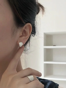 Close-up of S925 sterling silver shell earrings and wide matte ring on a female model