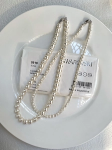 Macro detail of high-luster 5mm white crystal pearl necklace with silver metal clasp