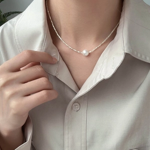 Dettaglio di una singola perla su una collana dorata sfaccettata sul collo