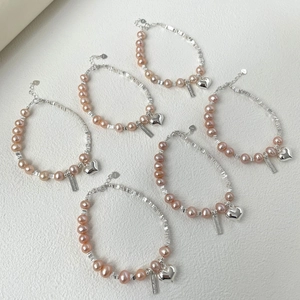 Détails macro des pendentifs cœur en argent S925 et perles d'eau douce roses sur bracelets