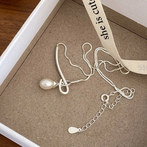 Detailed macro view of a silver-tone horizontal bar necklace with a white teardrop pearl