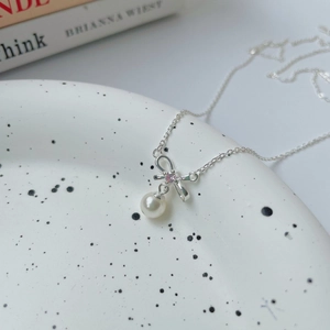 Detailed macro view of S925 silver bow pendant with white pearl and pink zircon