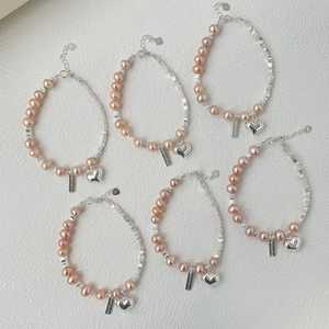 Détail du bracelet en perles d'argent S925 avec pendentif cœur et plaque de marque