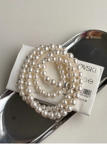 Macro view of creamy white round pearls with silver lobster clasp on a metal tray