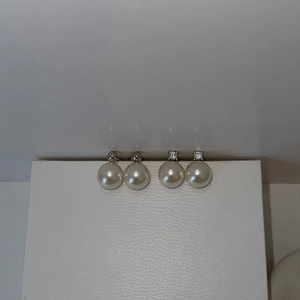 Close-up of pearl stud earrings with metallic spheres and clear zircon stone accents