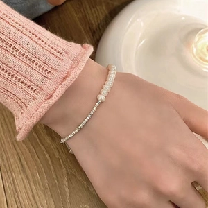 Close-up of fresh water pearls and silver chain bracelet worn on a female wrist