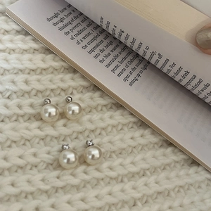 Macro shot of minimalist pearl earrings with silver base and rhinestone details