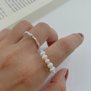 Detailed view of an S925 silver ring featuring five white pearls on a textured band