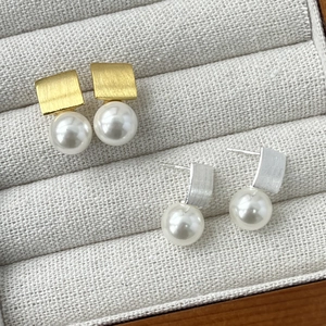 Detail of minimalist S925 silver square metal ear studs with high-luster pearls