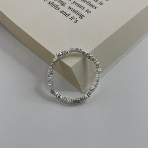 Macro shot of silver faceted beads ring with a smooth center sphere on a book
