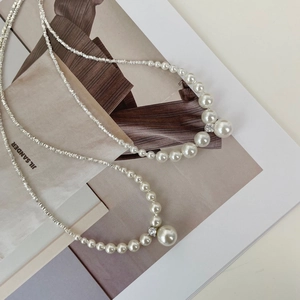 Elegant French style silver pearl necklace with central crystal on a fashion magazine