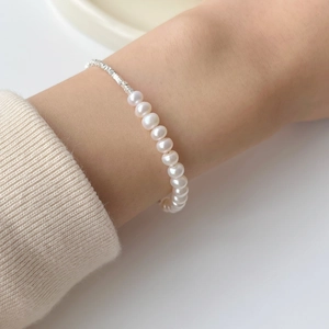 Close-up of natural freshwater pearls and silver nugget beads on a wrist bracelet
