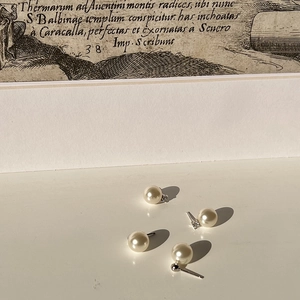 Detail of four cream faux pearl earrings with silver posts on a vintage background
