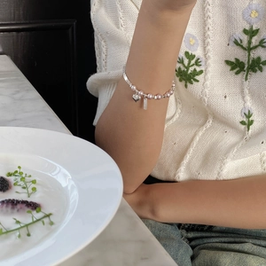 Détail du bracelet en perles et argent S925 avec pendentif cœur sur le poignet