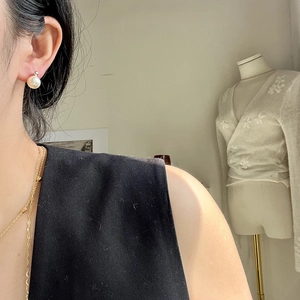 Detailed view of elegant white round pearl earrings on model with gold necklace