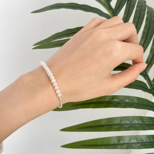Detailed view of genuine freshwater pearl bracelet with silver chain on female wrist