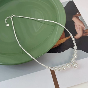Detail of silver fragmented chain necklace with gradient pearls and a heart pendant charm