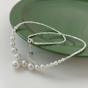 Detail view of gradient pearl necklace with central zircon and silver adjustable lobster clasp