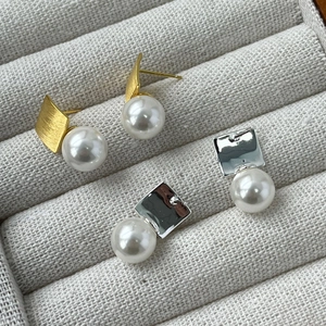 Macro shot of French retro pearl drop earrings in brushed gold and polished silver finish
