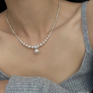 Elegant silver pearl necklace with a large pendant and rhinestone on collarbone