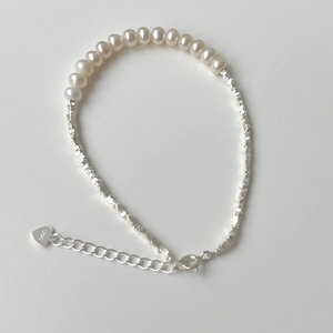 Detailed macro shot of 925 sterling silver heart charm and freshwater pearl bracelet