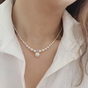 Detailed close-up of a large white round pearl pendant on a delicate pearl choker necklace