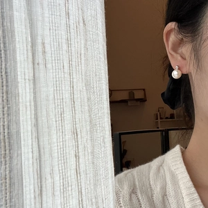 Close-up of elegant pearl stud earring worn on model featuring a silver metal accent