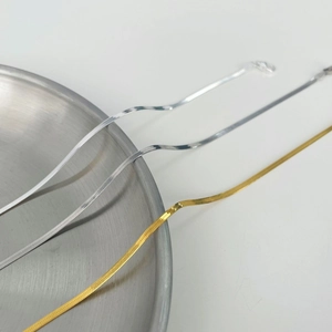 Detailed view of gold and silver S925 sterling silver snake bone chains on a metal tray