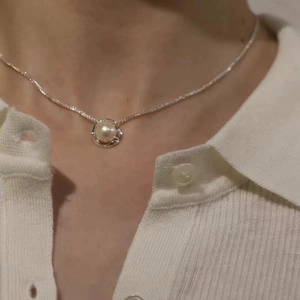 Detail of hollow silver pendant with natural freshwater pearl on 925 sterling silver chain