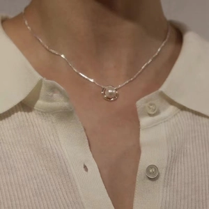 Close-up of minimalist 925 sterling silver necklace with hollow pearl pendant on neck