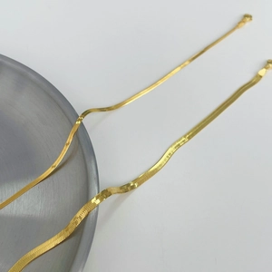 Flat gold snake bone chain necklaces in two widths on a brushed metal tray