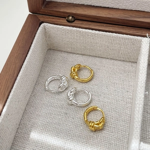 Detail of twisted double-layer geometric hoop earrings in gold and silver finishes