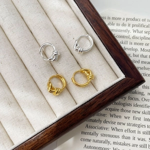 Detailed view of silver and gold knotted double layer hoop earrings in a wooden jewelry box