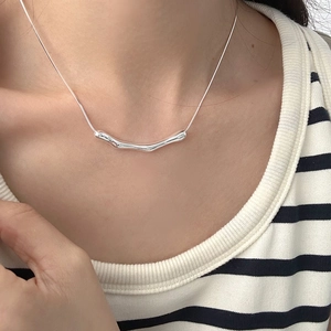 Detail of minimalist S925 sterling silver snake chain with irregular curved bar pendant