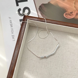 Close-up of minimalist S925 silver snake chain with an irregular curved bar pendant
