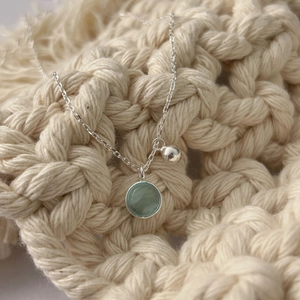 Detail of S925 sterling silver necklace with light green gemstone and round pendant