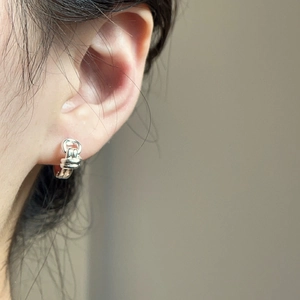 Close-up of a model wearing double-layered twisted silver knot hoop earrings in a minimalist style