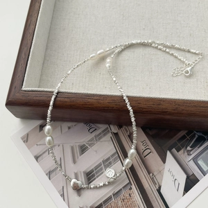 Dettaglio di ciondoli a cuore e smiley su una collana di perle e perline argentate
