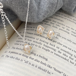 Detail of irregular natural pearl jewelry set with silver necklace and studs on book